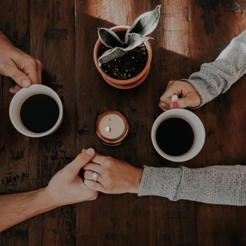 A couple holding hands and enjoying coffee at the Alex Hotel