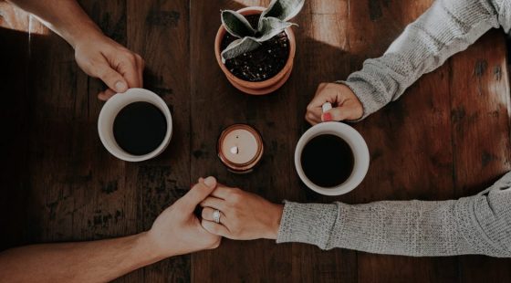 A couple holding hands and enjoying coffee at the Alex Hotel