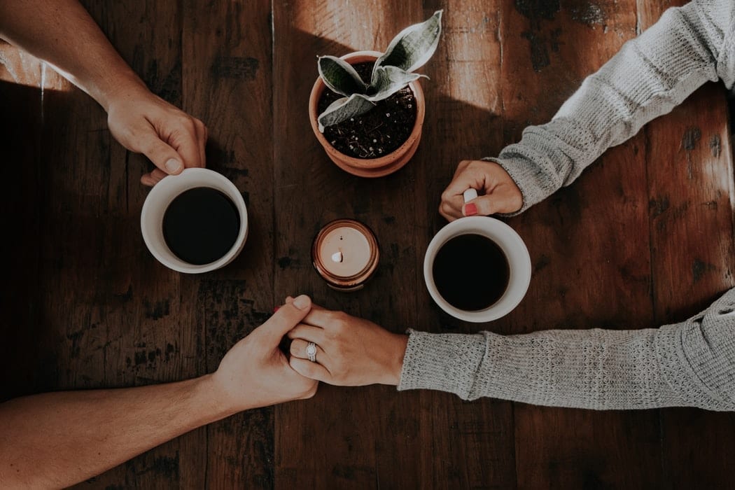 A couple holding hands and enjoying coffee at the Alex Hotel